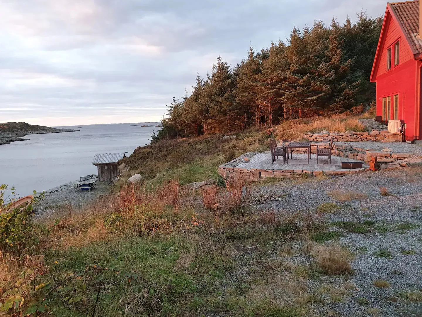Beverhuset — rødt feriehus på naturtomt rett ved sjøen, i kveldslys